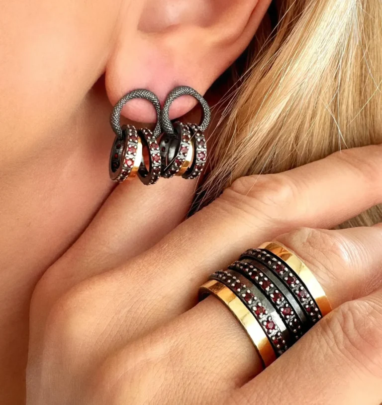 Earrings and stacked rings set with red stones, worn together