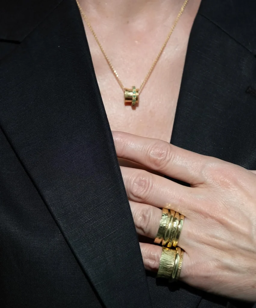 Hand with stacked 18K gold K.AND. rings against a black jacket