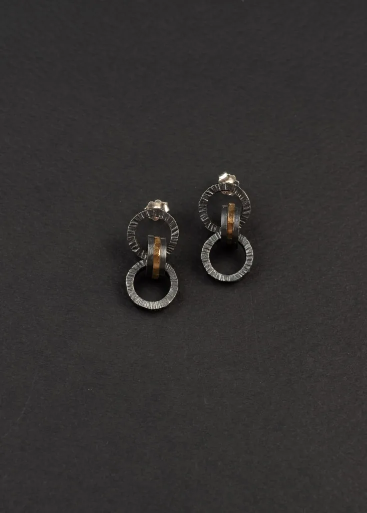 Mini hoop earrings with gold details on a dark grey background