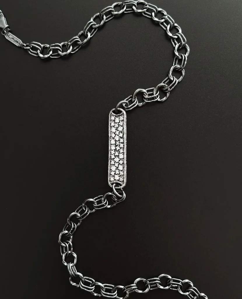 K.AND. chain with a pave set bar on a black background
