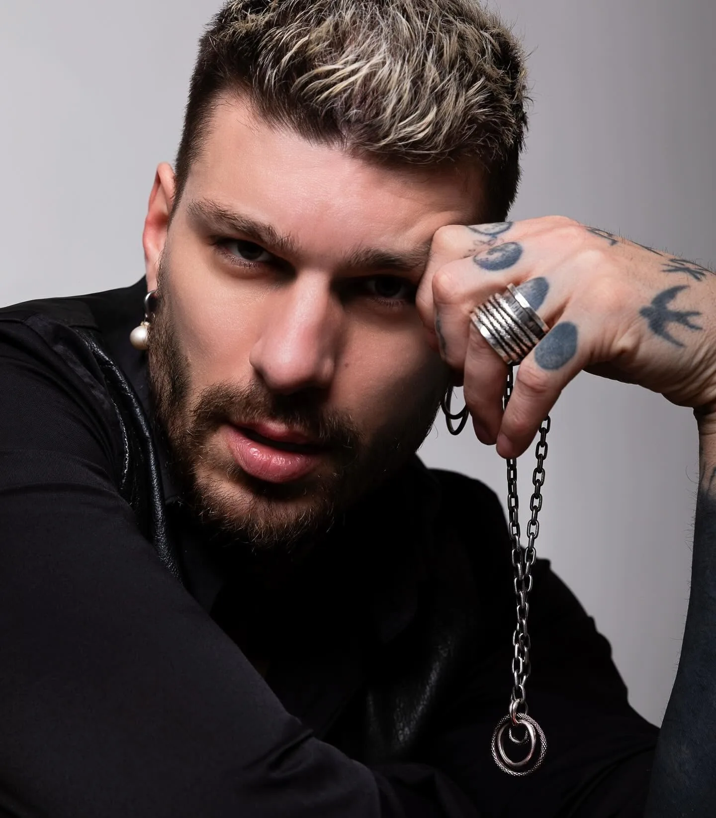 Man wearing several K.AND. silver rings and a chain, black and white portrait